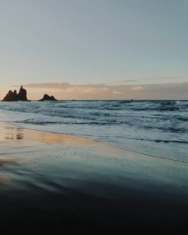 Silhouette sur une plage de sable noir au coucher du soleil, à Tenerife
